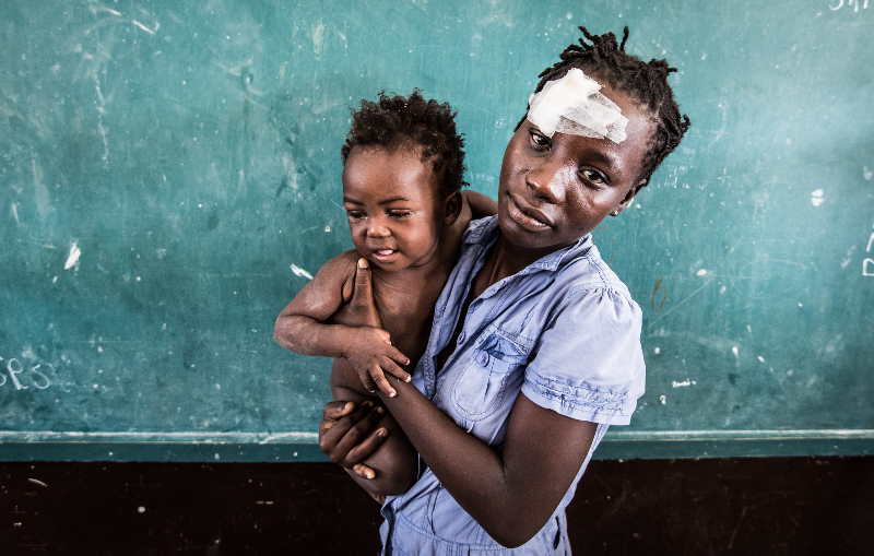 Haitianische Mutter mit Baby, die Mutter hat ein großes Plkaster auf der Stirn. (c) Mathiew Almeras/HI
